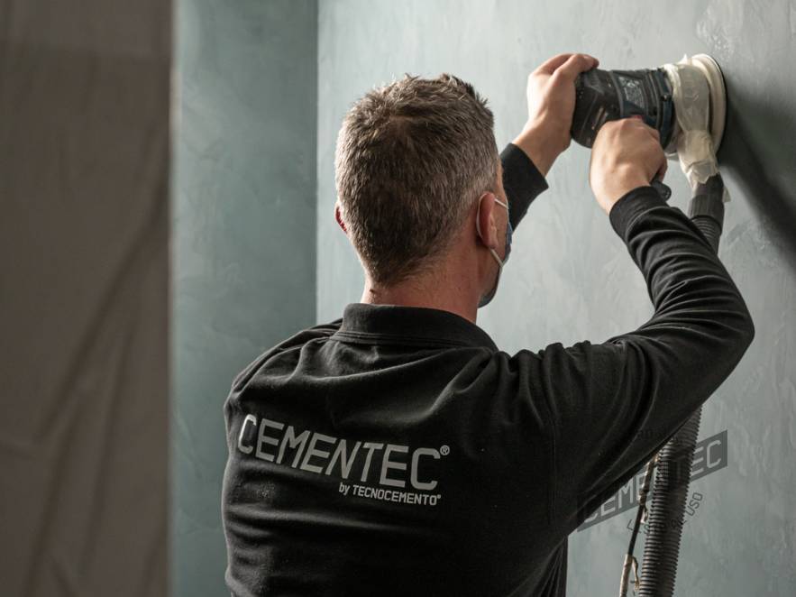 Uno de los aplicadores de microcemento listo al uso de Cementec lijando una pared.